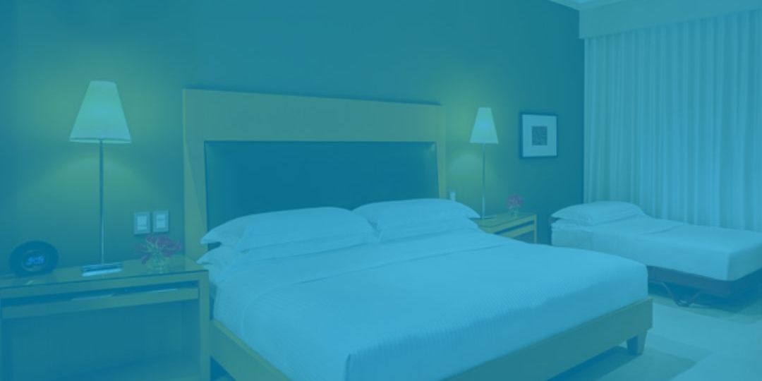quarto de hotel iluminado por dois abajures com luz amarelada