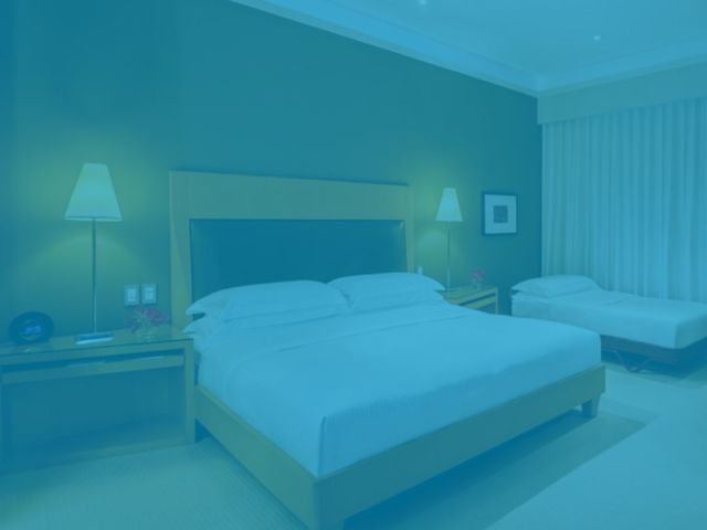 quarto de hotel iluminado por dois abajures com luz amarelada